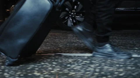 Man pulling black suitcase in underground parking 스톡 동영상 335474565