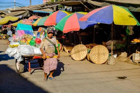 A man is pulling a cart full of goods at the vegetable market in the stree... 写真素材