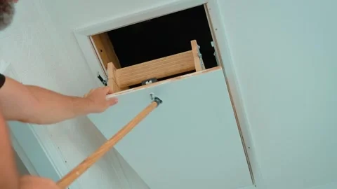 Man pulling down wooden loft ladder from open ceiling hatch for attic access Stock Footage 346285468
