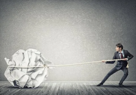 Man pulling with effort big crumpled ball of paper as creativity sign Stock Photos