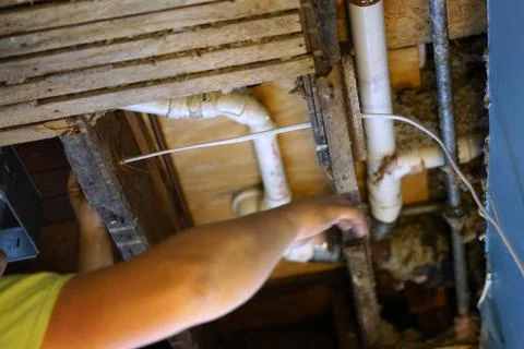 A man pulling electrical cable into the ceiling. Stock Photos