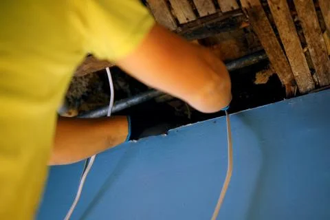 A man pulling electrical cable into the ceiling. Stock Photos