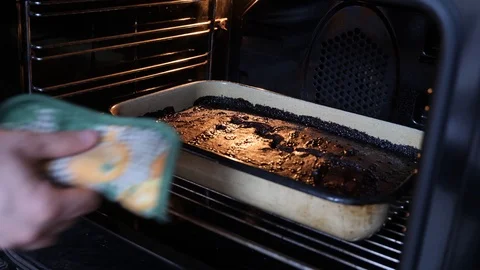 A Man Pulling a Freshly Baked Cake Out of the Oven Stock Footage 102627813