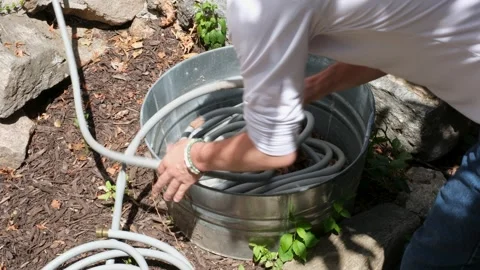 Man Pulling Garden Hose Out of Metal Tub in Backyard Stock Footage 337119871