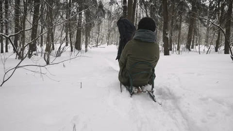Man pulling girl on a sled at snow. Winter fun Stock Footage 87297853
