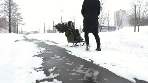 Man pulling girl on a sled at snow. Winter fun Stock Footage 99509880