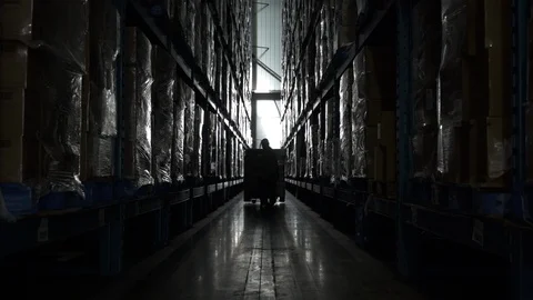 Man pulling hand held pallet truck in aisle of warehouse. Stock Footage 88028568