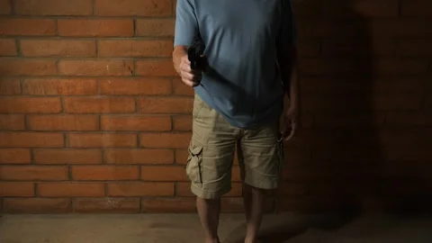 A man pulling a handgun in self defense in a dark alley Stock Footage 240951570