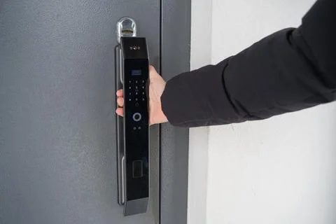 Man pulling handle of smart lock street door Stock Photos