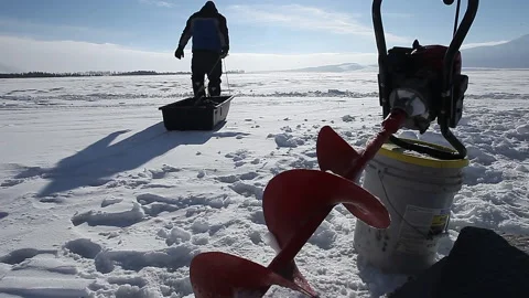 Man pulling ice fishing sled at western lake in winter Stock Footage 199712834