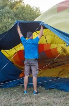 A man is pulling a large balloon out of a blue and yellow tent Foto stock