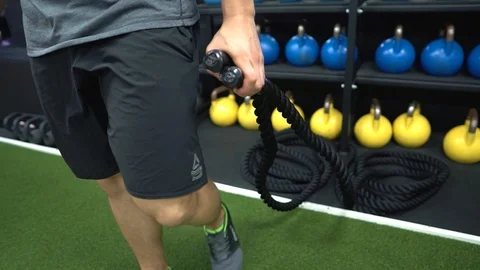 A man is pulling out the battle rope for his exercise in the gym. Stock Footage 128420522
