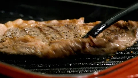 Man is pulling out well roasted steak from the grill Stockbeeldmateriaal 102611511