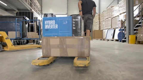 Man pulling a pallet jack carrying solar energy inverters at a warehouse Stock Footage 169021946