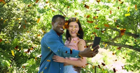 Man pulling phone from pocket, couple posing selfie in garden, gold confetti Stock Footage 322182325