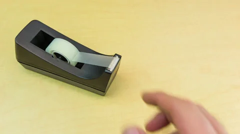 Man pulling off a piece of tape from tape dispenser Stock Footage 32243326