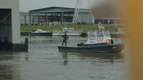 A man pulling on a robe bring in a tug boat into a marine, static wide shot Video stock 209385938