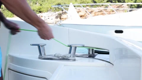 Man pulling a rope of anchor and tying it on yacht. Stock Footage 137673424