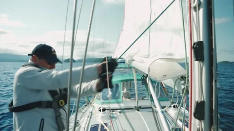 Man pulling on ropes and hoisting sail on a sailboat. Stock Footage 236533149