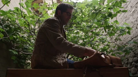 Man pulling sketch book out of his back pack outdoors Stock Footage 68186924