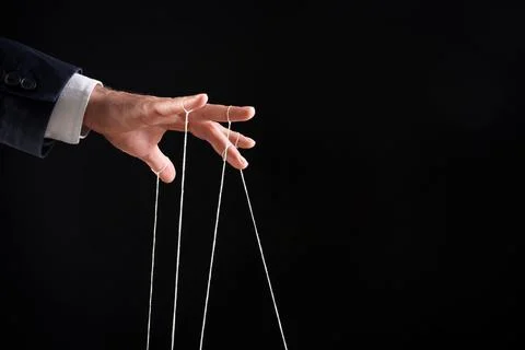 Man pulling strings of puppet on black background, closeup. Space for text Stock Photos