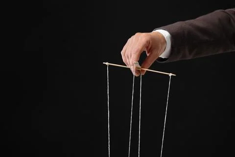 Man pulling strings of puppet on black background, closeup. Space for text Stock Photos