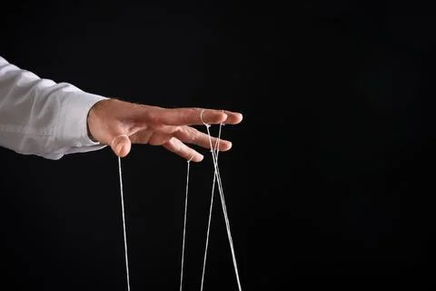 Man pulling strings of puppet on black background, closeup. Space for text Stock Photos