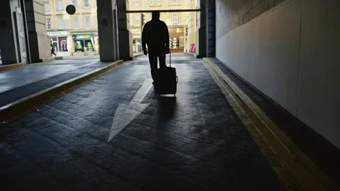 Man pulling a suitcase exits underground parking by going against the down arrow Stock Footage 242815617