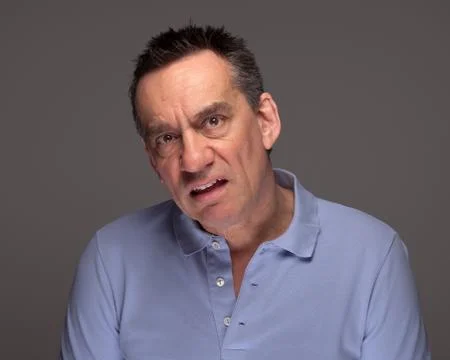 Man pulling unhappy face on grey background Stock Photos