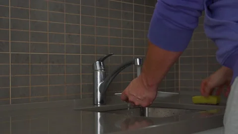 Man in pullover washes plate in kitchen sink with sponge Stock Footage 119596778