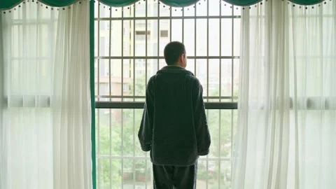 Man pulls back the curtains to greet a new day when he gets up in the morning 스톡 동영상 330833790