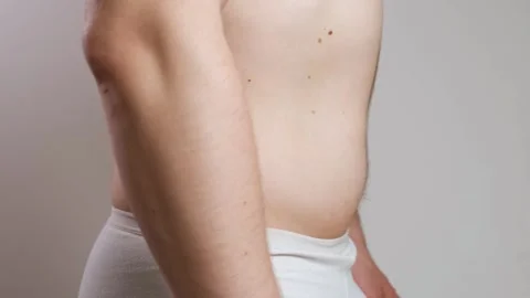 A man pulls in a big belly and strains his abs in close-up. The concept of diet Stock Footage 241415335