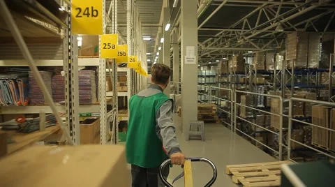 Man pulls a cart with a load in a huge warehouse Stock Footage 64044738