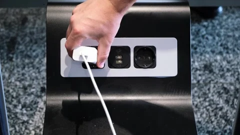 A man pulls the charger plug out of the socket in a public place. Stock Footage 301770608