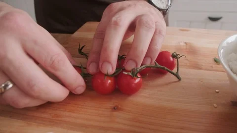 A man pulls cherry tomatoes from a stalk with a kitchen Stock Footage 125934268
