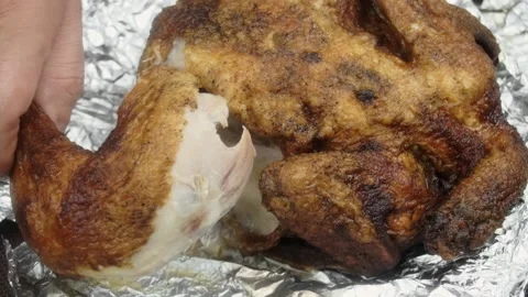 A man pulls a chicken leg out of a baked chicken. Close-up Vídeo Stock 145628088