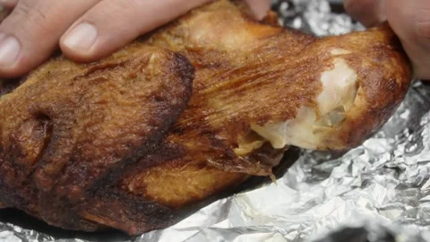 A man pulls a chicken leg out of a baked chicken. Close-up Vídeo Stock 145628157