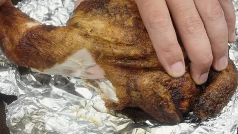 A man pulls a chicken leg out of a baked chicken. Close-up Vídeo Stock 145628253