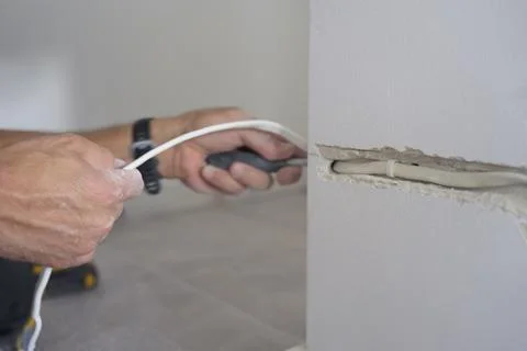 Man pulls electrical cable through a channel cut into an interior wall Stock-Fotos