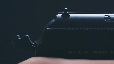 The man pulls the hammer and shoots with gun on black background Видео 128321955