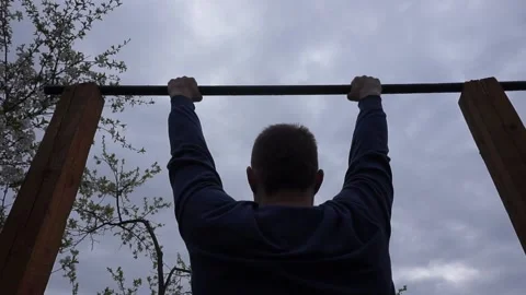 A man pulls himself up on a horizontal bar. Stock Footage 130594095