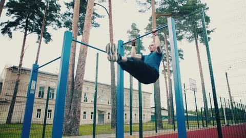 A man pulls himself up on a horizontal bar making a corner, exercising on Stock Footage 149754828