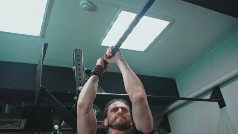 A man pulls himself up on a horizontal bar in the gym Stock Footage 153585963