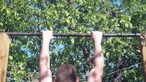 A man pulls himself up on a horizontal bar. view from the back. naked torso Stock Footage 165883212