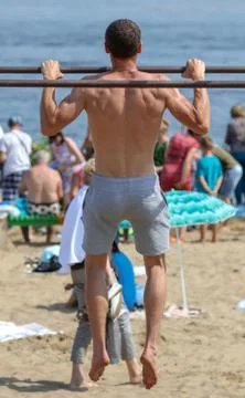 A man pulls himself up on a horizontal bar in the park Fotos Stock