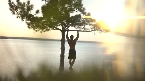 Man pulls himself up on a tree branch Stock Footage 129105560