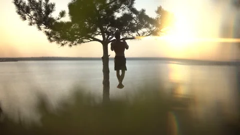 Man pulls himself up on a tree branch Stock Footage 129105564