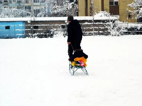 A man pulls his child with the sleigh Stock Photos
