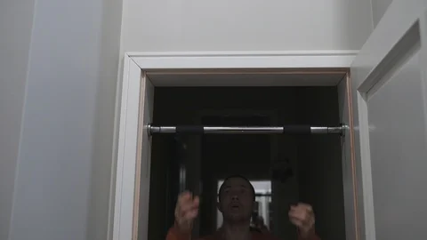 Man pulls up on horizontal bar at home, 4 K Video stock 124415397