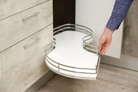 Man pulls a kitchen carousel out from the bottom drawer of a cabinet in a mod Stock Photos